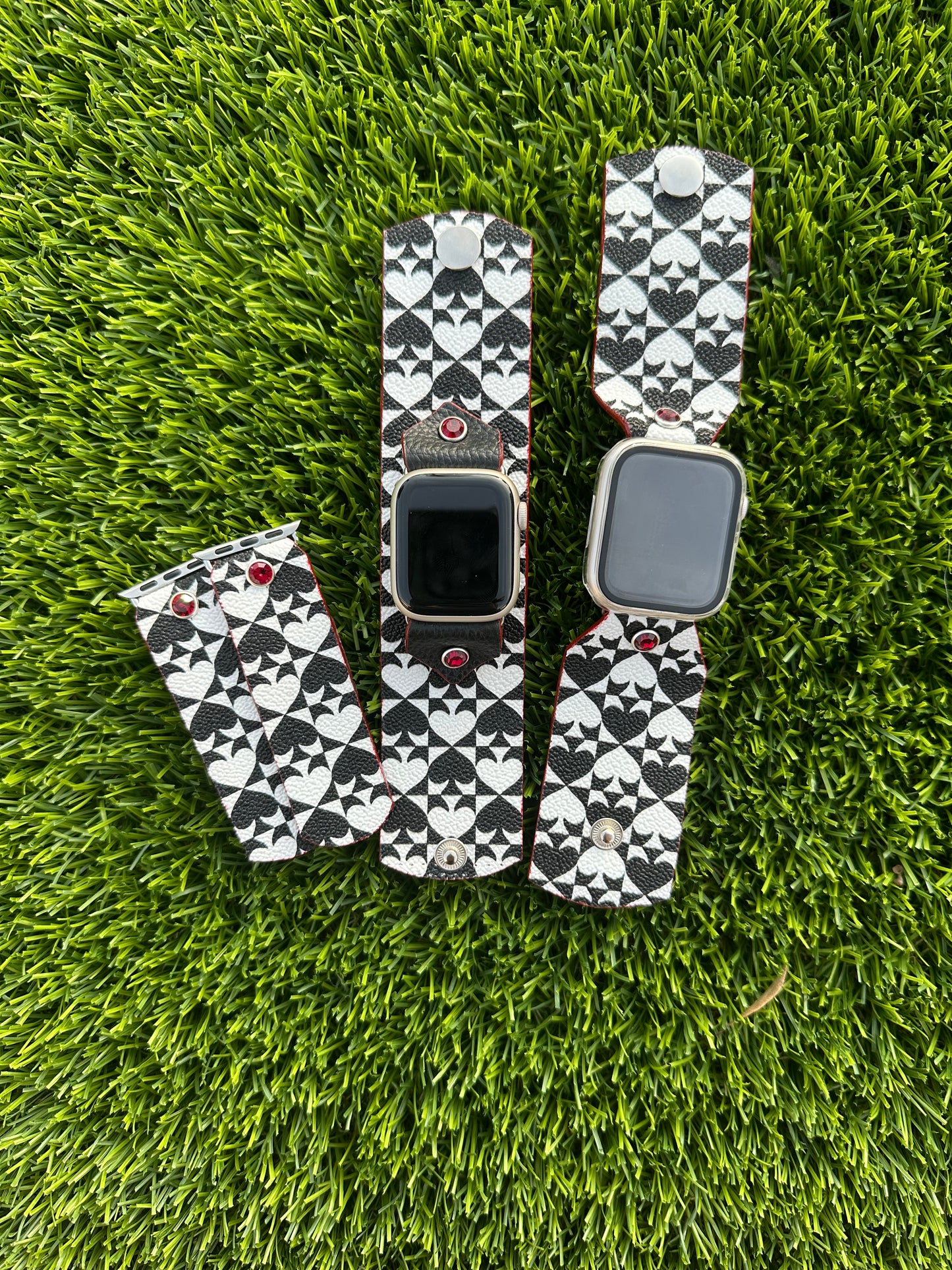 An upcycled Kate Spade band. This band is made from a PVC coated canvas. The design consists of an alternating black and white pattern with a red leather lining and matching edge paint. The band is embellished with a red silver rimmed crystal with matching hardware.