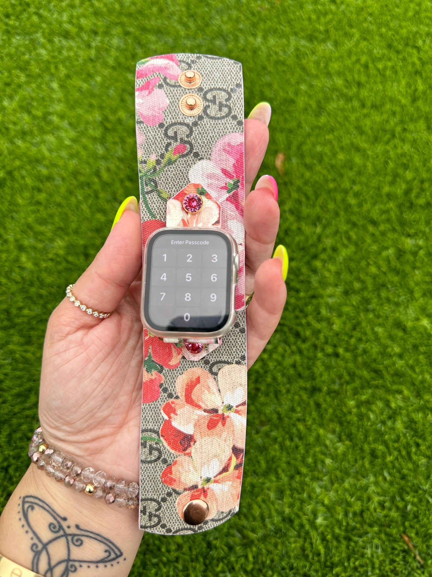 This is an authentic upcycled Pink Gucci Bloom. It is a canvas band material with the iconic GG monogram with pink flowers in the pattern. This is a single layer band with pink edge paint. The band is paired with a yellow gold rimmed rose crystal and rose gold hardware.