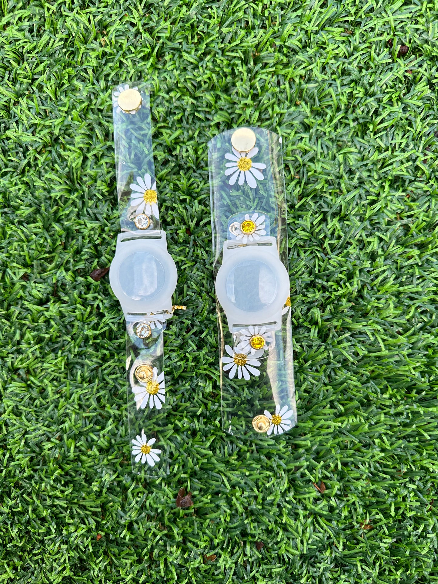 Anya style transparent PVC waterproof band perfect for all year round. The band has scattered daisies with a glittery gold center. The design is embellished with clear crystals with a gold rim. Frosted White Air Tag holder will act as the band's center.