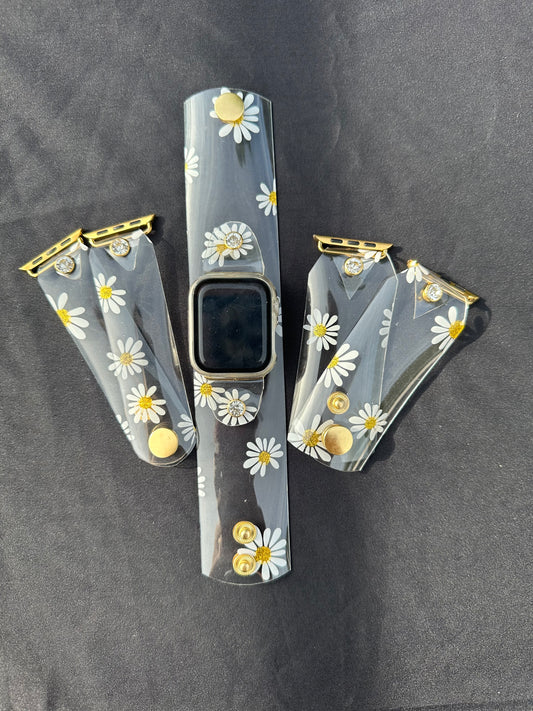 A transparent PVC waterproof band perfect for all year round. The band has scattered daisies with a glittery gold center. The design is embellished with clear crystals surrounded by a gold rim.
