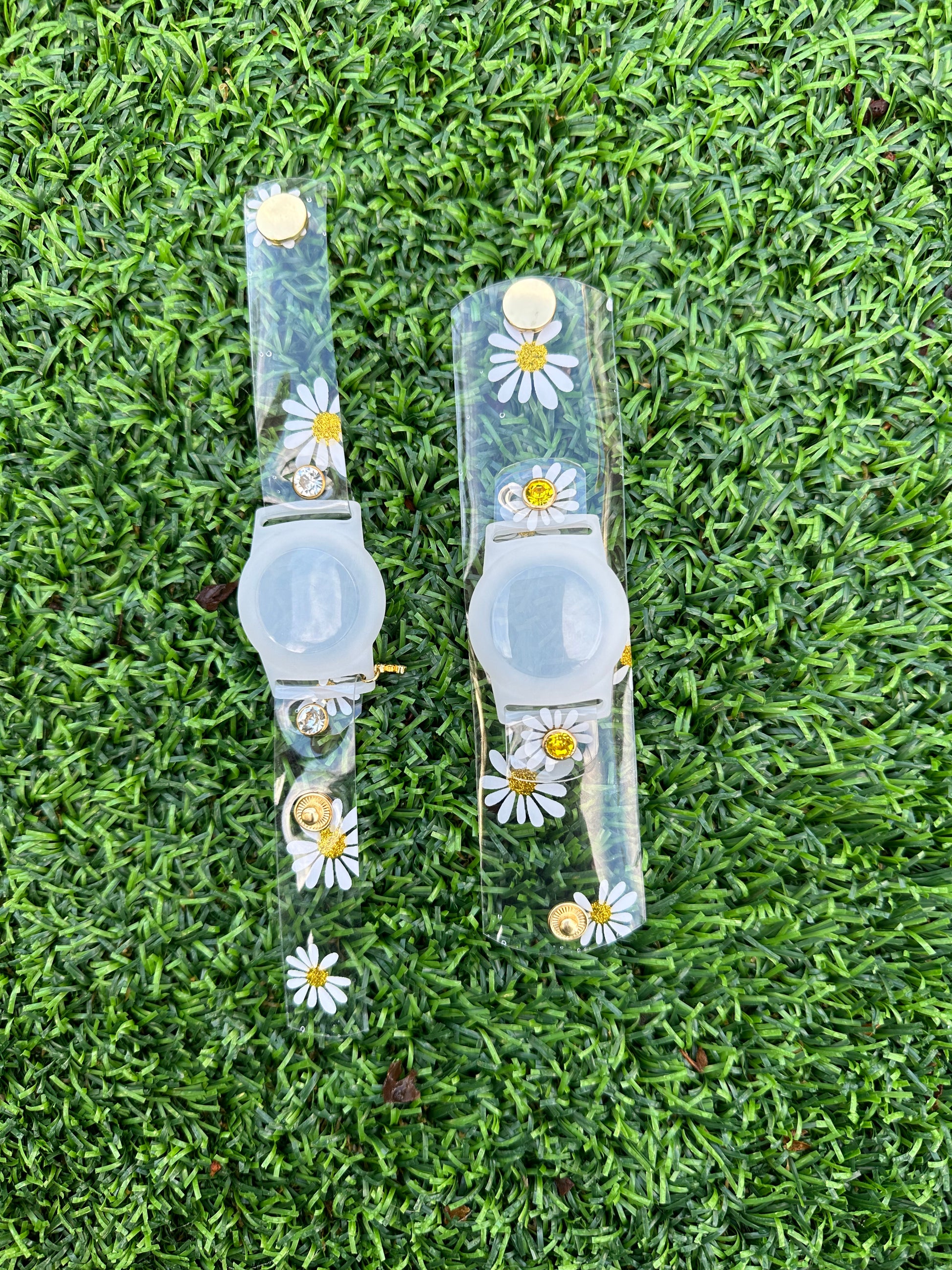 Anya style transparent PVC waterproof band perfect for all year round. The band has scattered daisies with a glittery gold center. The design is embellished with clear crystals with a gold rim. Frosted White Air Tag holder will act as the band's center. 