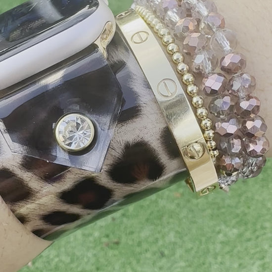 A transparent PVC waterproof band perfect for all year round. It's great to wear it to work out, be outside, and get wet. The band is a scattered leopard cheetah animal print with a brown center. The design is embellished with clear crystals surrounded by a gold rim.