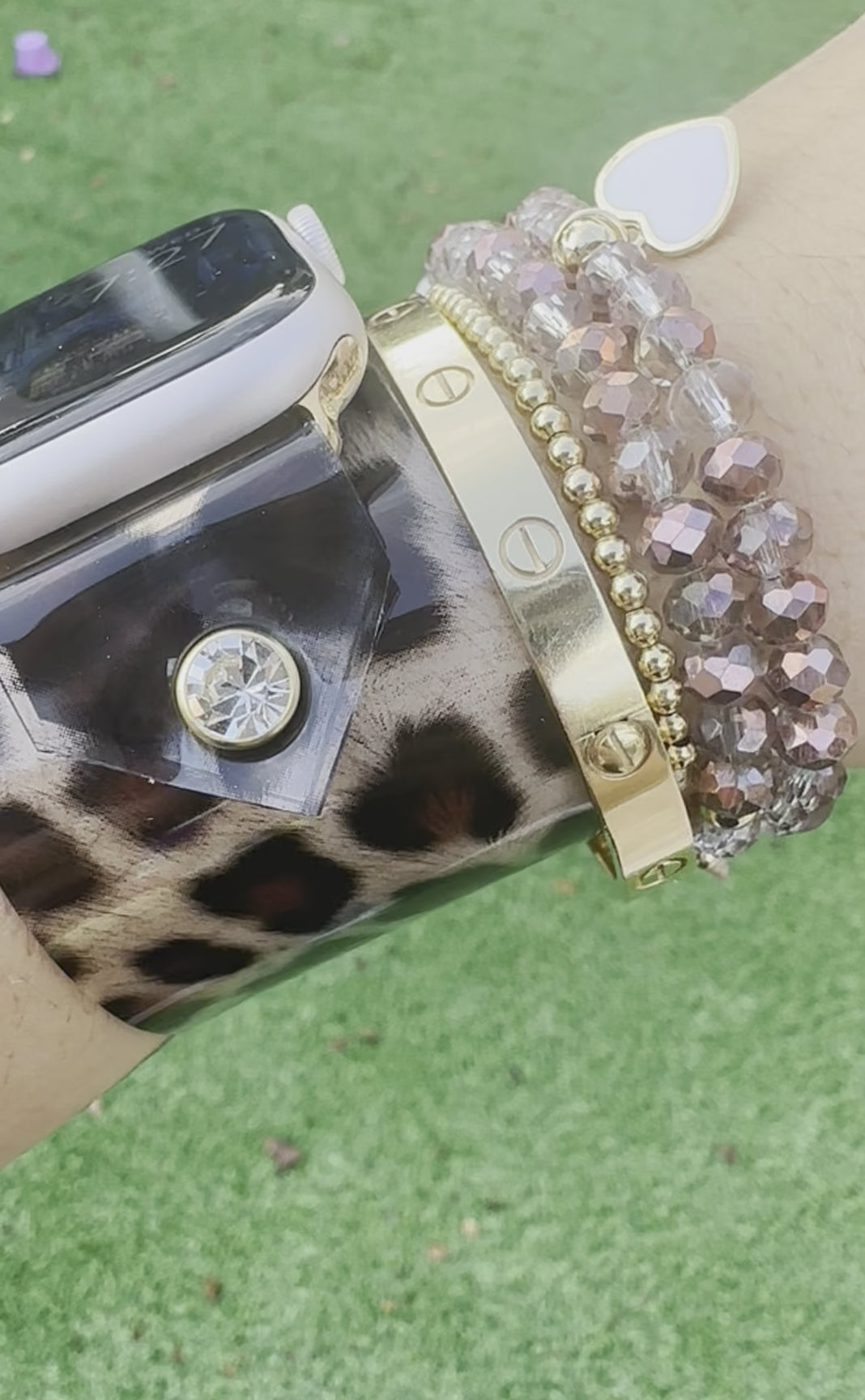 A transparent PVC waterproof band perfect for all year round. It's great to wear it to work out, be outside, and get wet. The band is a scattered leopard cheetah animal print with a brown center. The design is embellished with clear crystals surrounded by a gold rim.